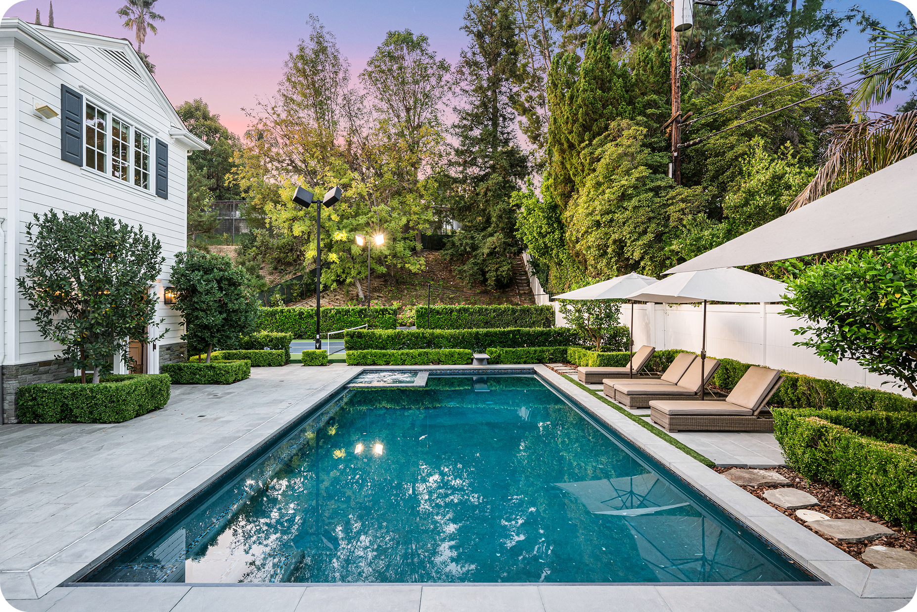 Backyard pool with lounge chairs and trees.