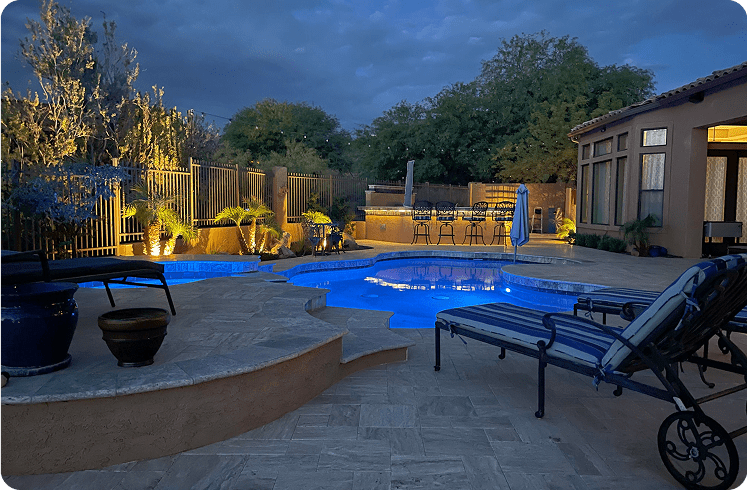 Illuminated backyard pool area at night.